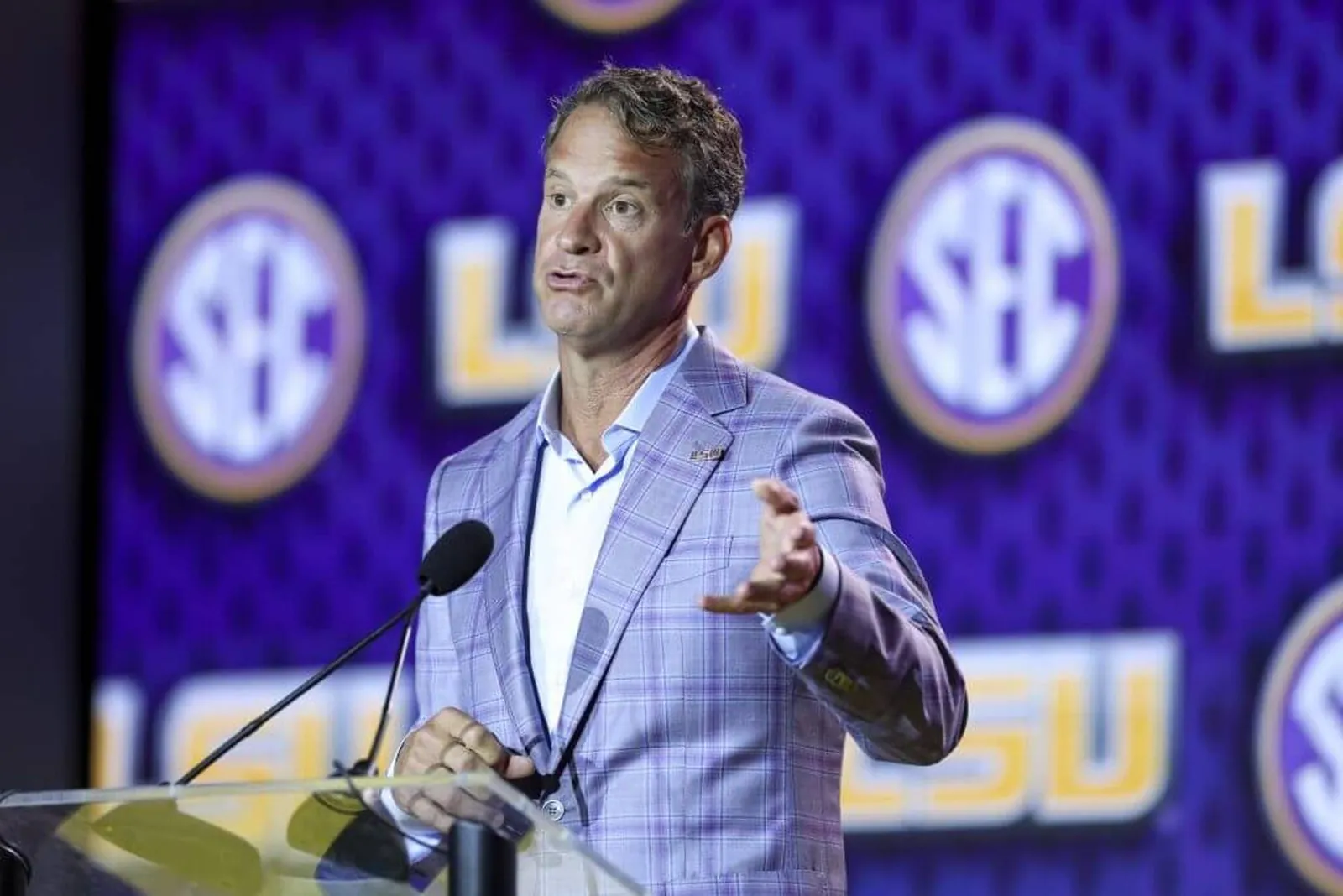 LSU football coach Lane Kiffin gestures with his left hand while speaking in front of a podium at SEC Football Kickoff Media Day at the Tampa Marriott.