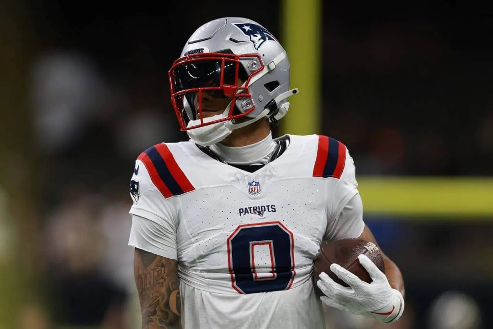 New England Patriots cornerback Christian Gonzalez holds a football.