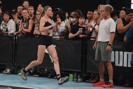 Joanna Wietrzyk runs past a crowd taking photos during a HYROX competition