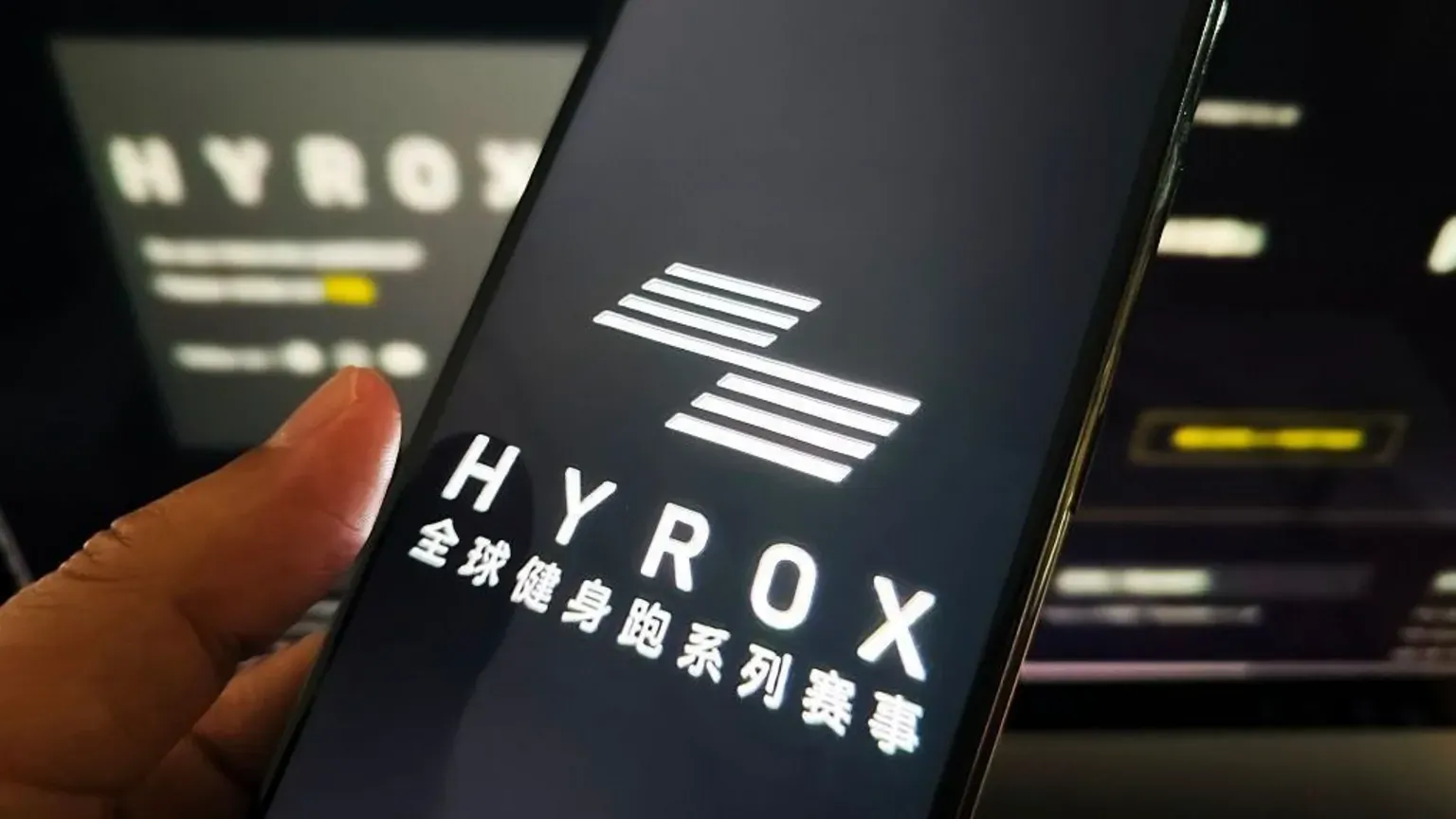 Getty Images A woman holds a mobile phone with Hyrox branding on it.